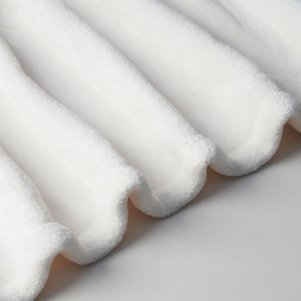 Fluffy white fleece blanket, soft with a warm, embossed texture. Made from recycled polyester for comfort and sustainability.