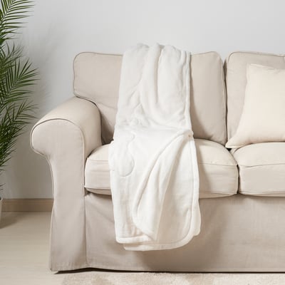 Beige sofa with rolled white blanket. Soft, warm, and recycled fleece fabric for cosy comfort.