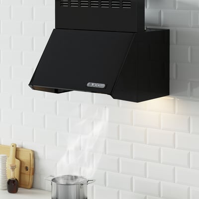 Black range hood on white brick wall, sleek and angular, with countertop items below.
