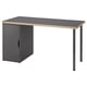 An ikea LAGKAPTEN desk in dark gray with a honeycomb-patterned edge. It a storage cabinet with a door and black legs.