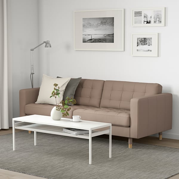 A modern living room with a LANDSKRONA beige leather 3-seat sofa, stylish white coffee table, grey rug, and black and white wall art.