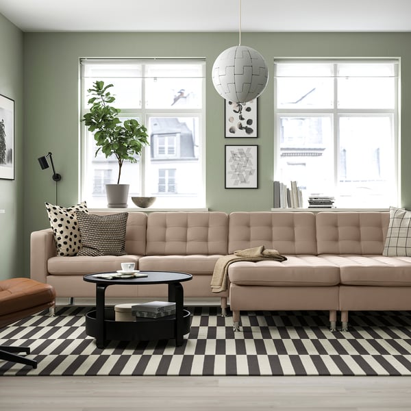 Modern living room with beige sectional sofa, black & white decor, large windows.