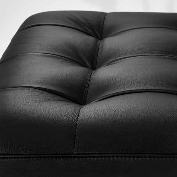 Black leather sofa close-up, showcasing high-quality stitching and smooth texture.