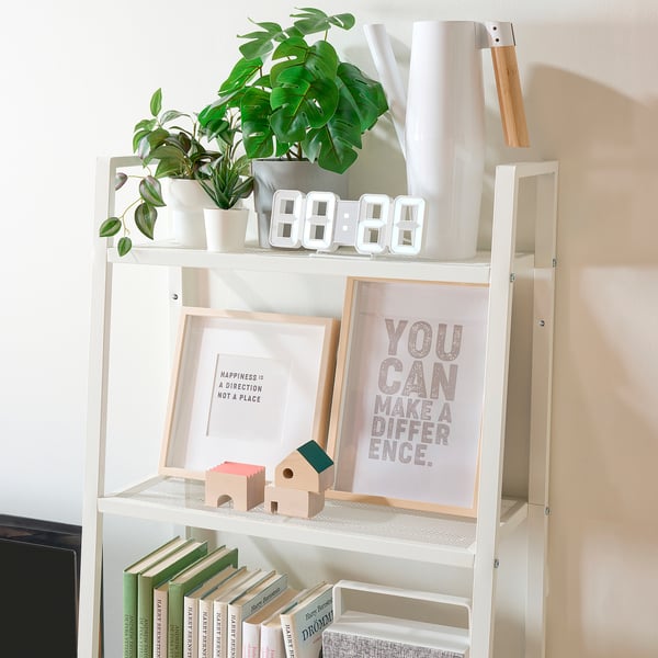 White shelf unit displaying books, plants, and decor; securely anchored to wall.