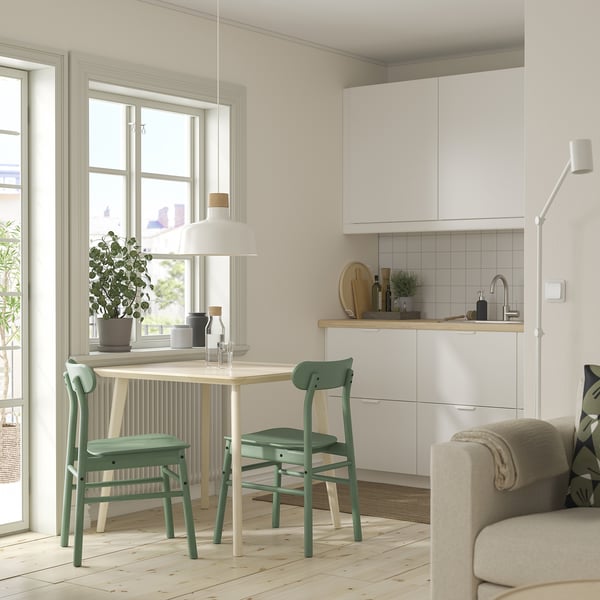 Small, compact dining set with clear table & green chairs. Modern, minimalist design. Ideal for tight spaces.