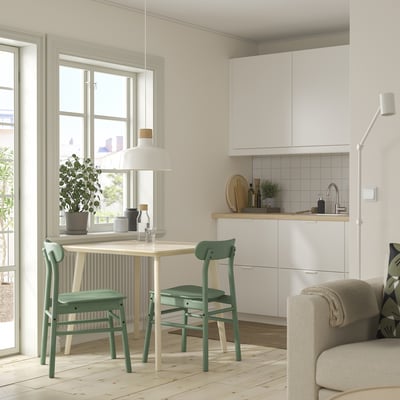 Small, compact dining set with clear table & green chairs. Modern, minimalist design. Ideal for tight spaces.