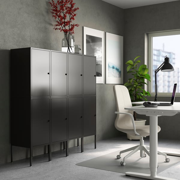 Modern office black LIXHULT storage cabinets, sleek desk with chair, colourful painting, and a laptop.