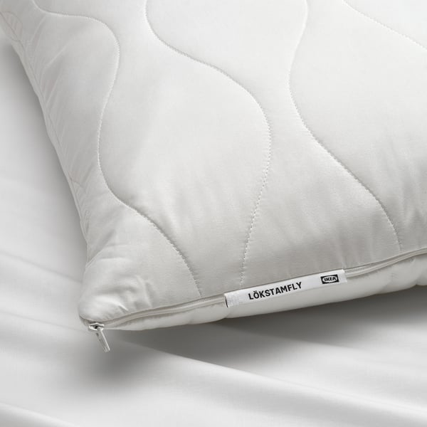 Close-up of LÖKSTAMFLY pillow with quilted texture; zip visible, showcasing quality craftsmanship.