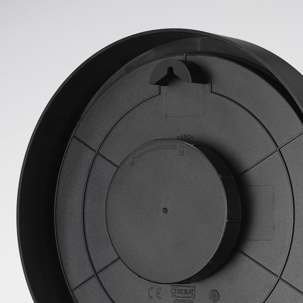 Black round clock with central dial, thick minute hand, raised hour markers, and wall mount option. Et.