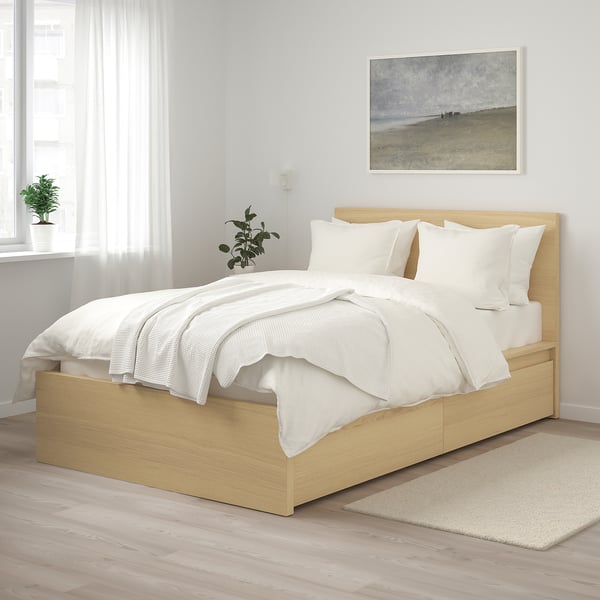 Modern bedroom with light brown MALM bed, white linens, picture, and plants.