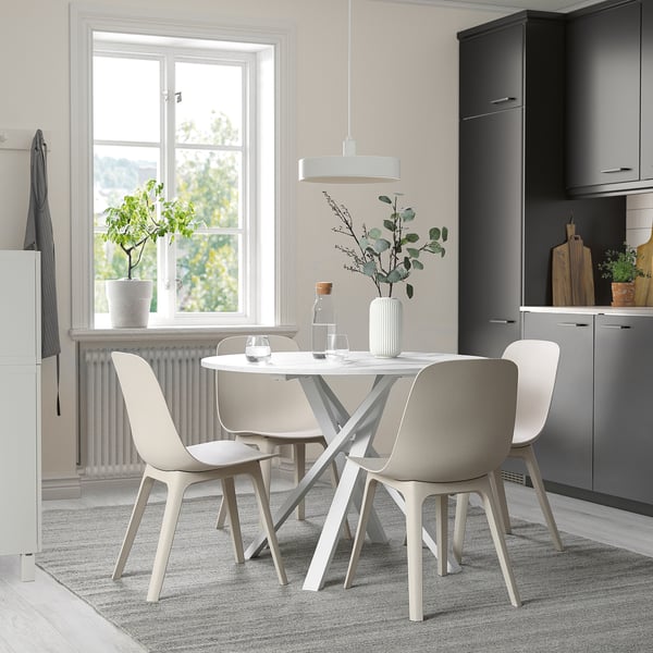 Round metal table with criss-cross legs, four chairs, large window.