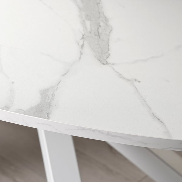Close-up of a sleek, white tabletop with subtle grey veining, supported by sturdy metal legs, showcasing modern design and quality construction.