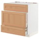 A white METOD kitchen cabinet with oak drawers, featuring a natural wood grain texture and soft-close drawers.