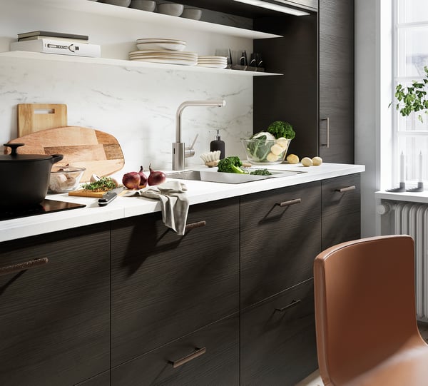 Modern kitchen with dark grey cabinets, white marble backsplash, and light brown chair.