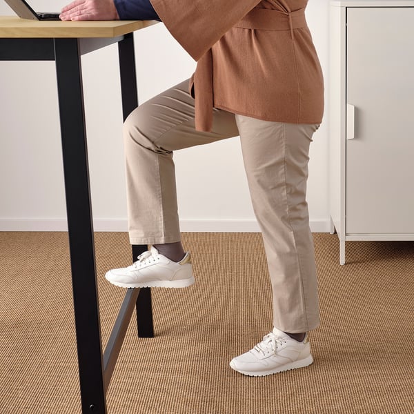 Person using high table with footrest, likely for standing or brief sitting, ideal for quick meetings or work tasks.