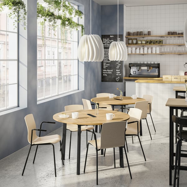 Modern cafe with wooden tables, large window, lamps, and counter. Intimate setting.