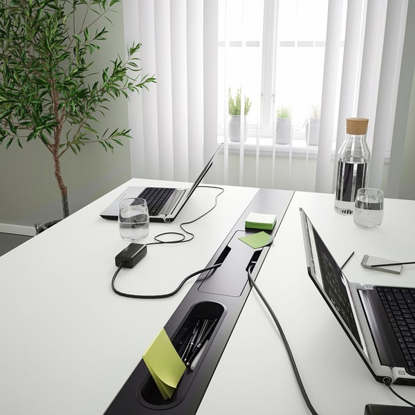 Modern conference table with tech and plants.