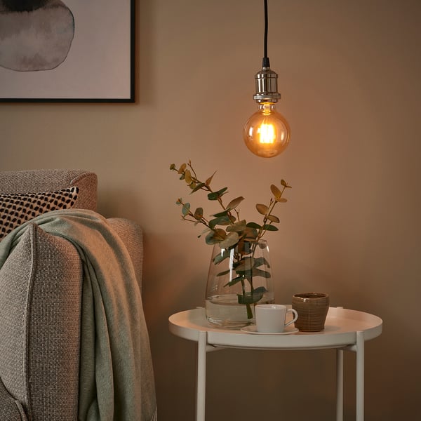 Amber led bulb above table with eucalyptus, coffee set, and blanket.