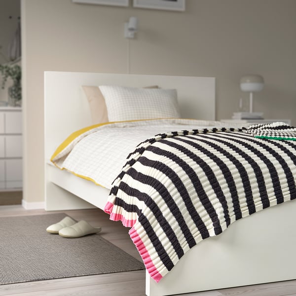 Modern bedroom MOSSMOTT black & white striped throw on white bed, oversized pillows, and cosy slippers.