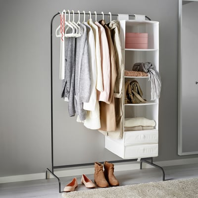 Clothes rack with hanging garments, shelves, and storage bins, featuring plastic feet to prevent scratching surfaces.
