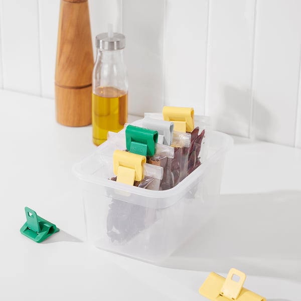 Clear container with food, color-coded clips, wooden bottle, & oil dispenser.