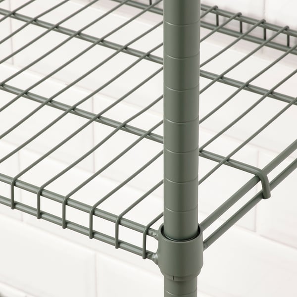 Close-up of sturdy, green industrial-style metal shelf on a tall post, showing strong wire mesh design.