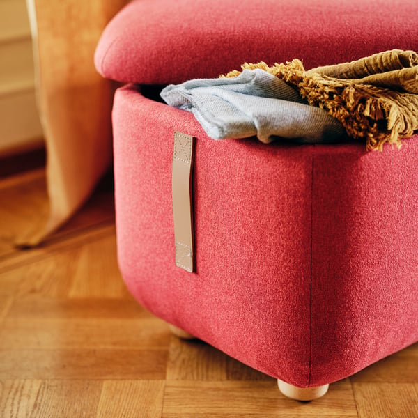 Vibrant red footstool with leather handle, showcasing quality design and storage space.
