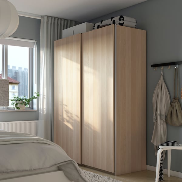 Minimalist bedroom with light PAX wardrobe, bed, and natural light.