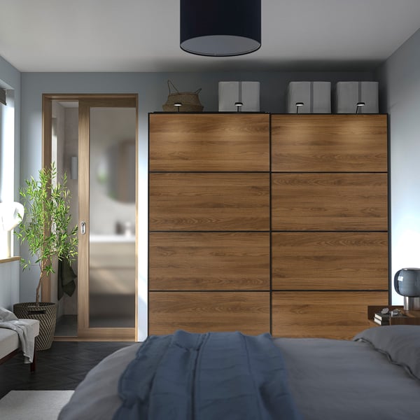 Modern bedroom with large wooden PAX wardrobe. Sliding doors save space, matches grey bed linen. Plants and storage boxes decorate.