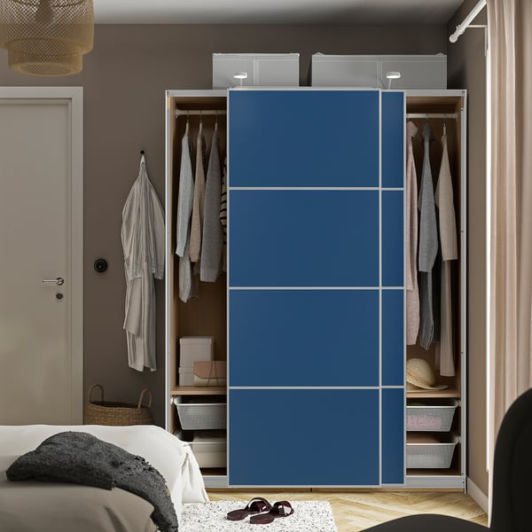 Bedroom with PAX wardrobe featuring sliding doors, hanging clothes, shelves, and storage boxes.