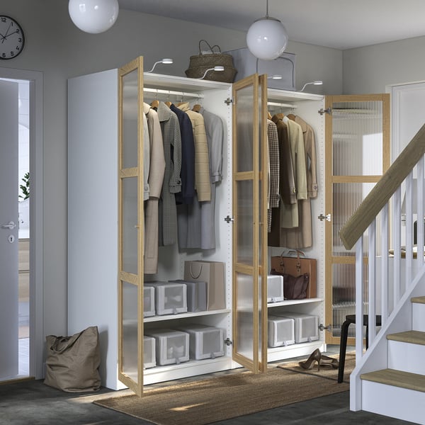 Modern closet with glass doors hanging clothes, shelves, and storage bins; includes integrated lighting and adjustable feet for stability.