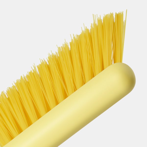 Close-up of a yellow brush with plastic bristles attached to a rounded handle, showing quality and detail.