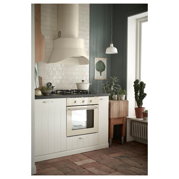 Modern kitchen: white cabinets, green walls, brick floor. Stainless appliances, plants, hanging lamp, art, bench.