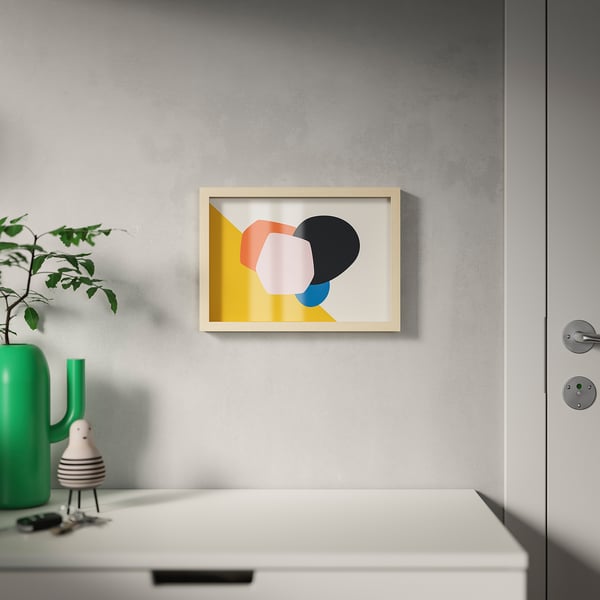 Framed modern art hangs centred on a grey wall above a white drawer. The frame can hang or stand, with various mounting options.