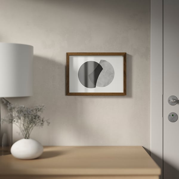 Minimalist room: framed abstract art hangs above wooden table with lamp and vase.