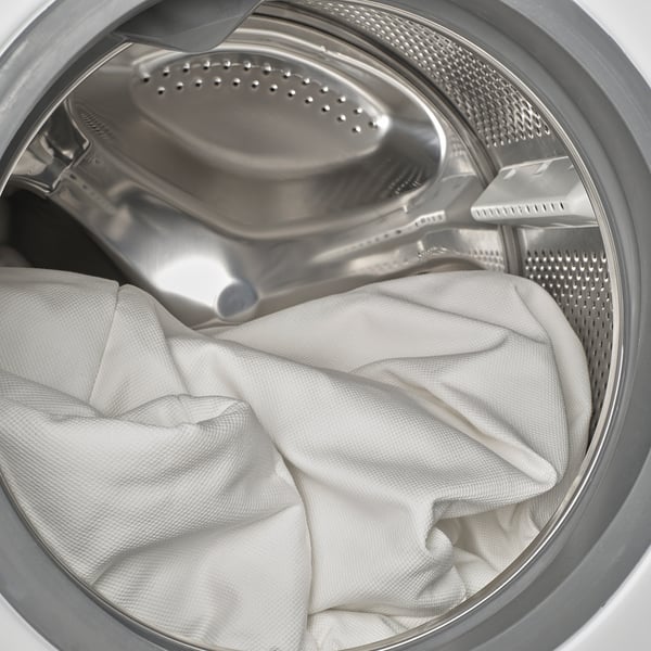 Washing machine drum with white laundry inside, ready for a spin cycle.