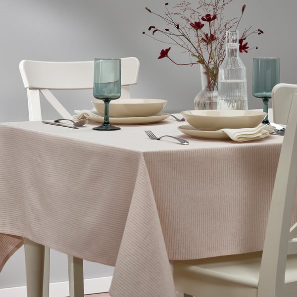 Table set with white chairs, bowls, glasses, cutlery, and a pink-striped tablecloth.