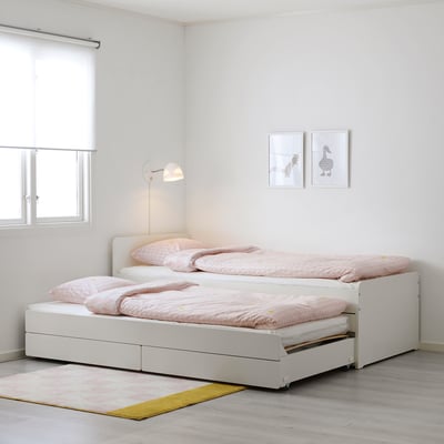 SLÄKT daybed with pull-out beds, pink dot bedding, under window, next to wall decor, yellow-pink rug on wood floor. Modern & space-saving.