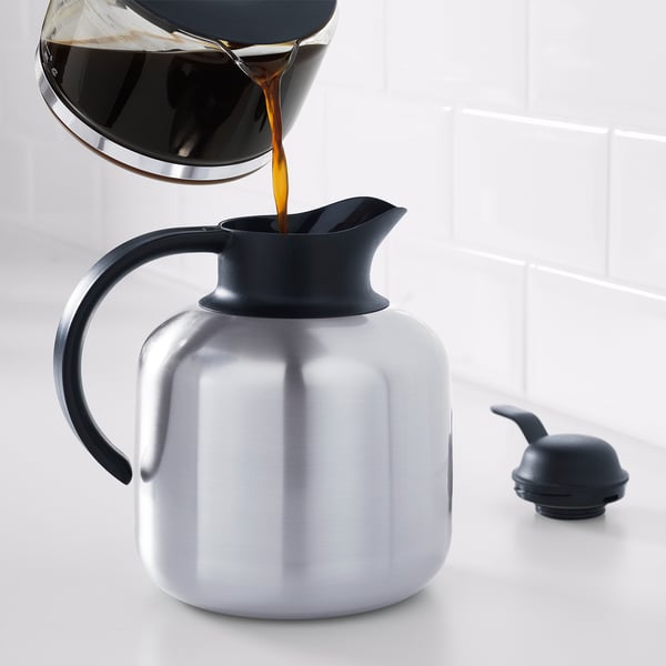 Coffee pours from dripper into sleek, silver vacuum flask with black lid, emphasising its insulation and pour efficiency.