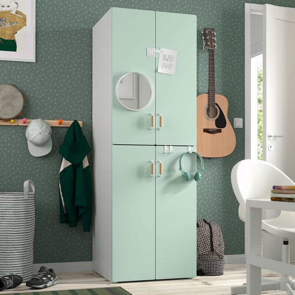 Mint green SMÅSTAD wardrobe with doors, mirror, guitar, coat rack, and chair with books.