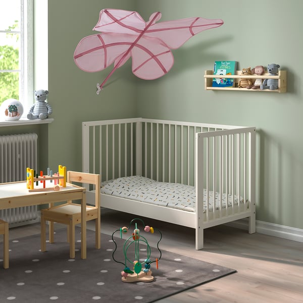Childs room with SNÖFINK canopy, crib, table, chairs, & toys. Green walls, window.