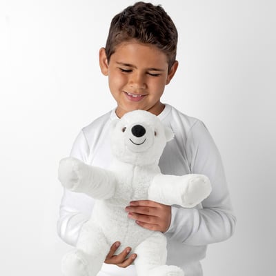 Young boy smiling while hugging a plush white polar bear teddy, ideal for comfort and snuggling.