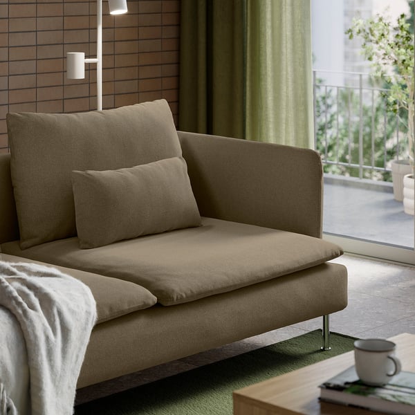 Modern, low-profile sofa with deep seats and loose cushions for comfort. Light, minimalist design with high legs. Placed near a window with curtains.
