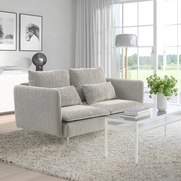 Modern minimalist living room with grey SÖDERHAMN sofa, white coffee table, vase, and large window.