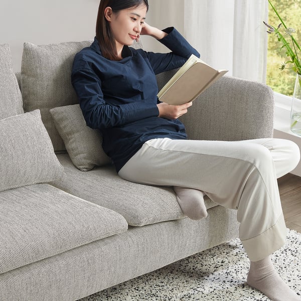 Person reading on SÖDERHAMN sofa. Compact beige-brown fabric. Cosy, deep seats with moveable cushions. Ideal for small spaces, fits near table.