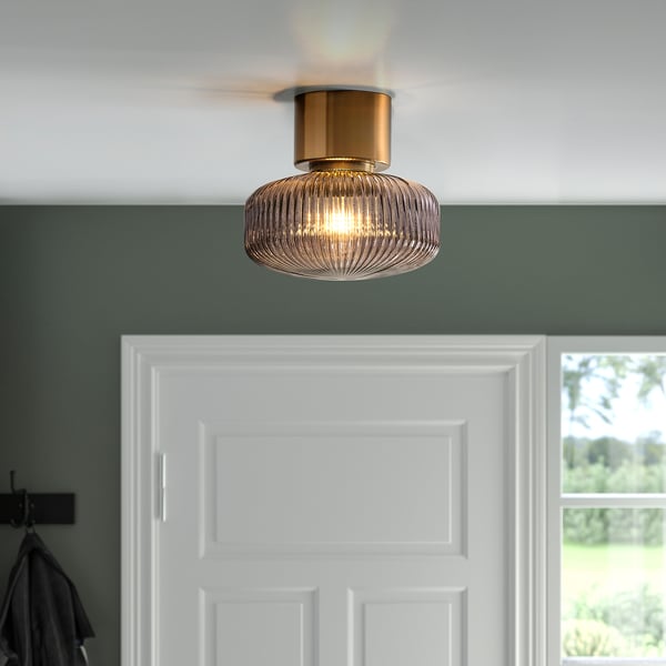Ceiling light with brass and glass shade, emitting soft mood light.