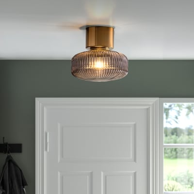 Ceiling light with brass and glass shade, emitting soft mood light.