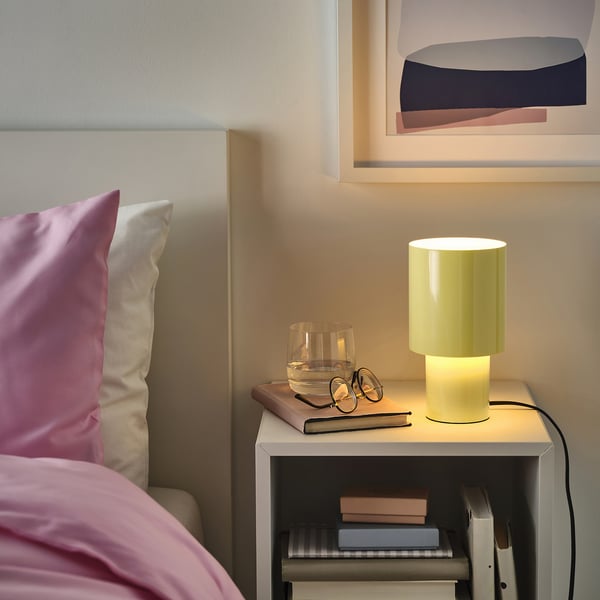 Modern bedroom with SPETSBOJ lamp on bedside table, casting warm glow.
