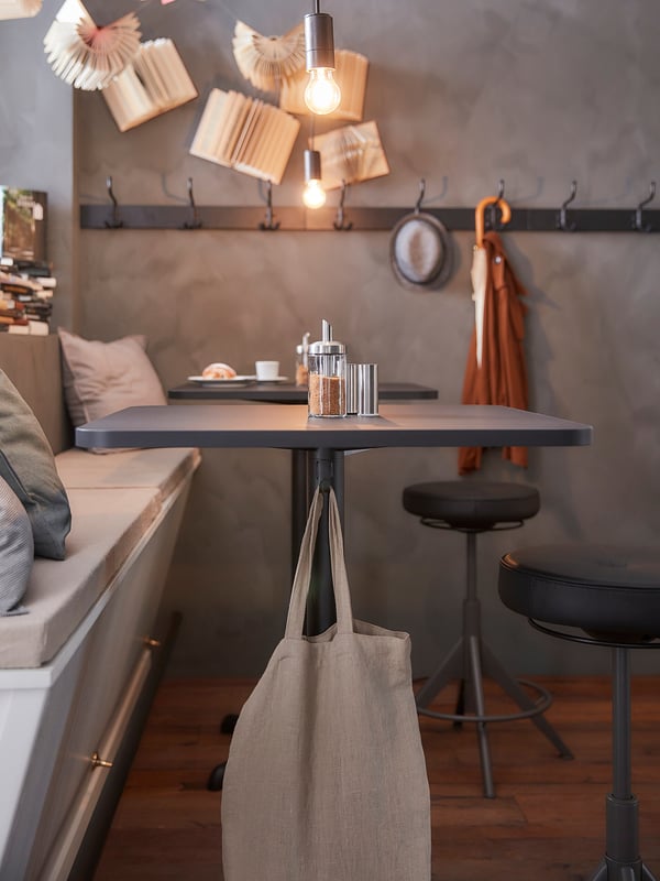 Modern kitchen with grey STENSELE bar table, bench, and stool. Beige tote underneath.