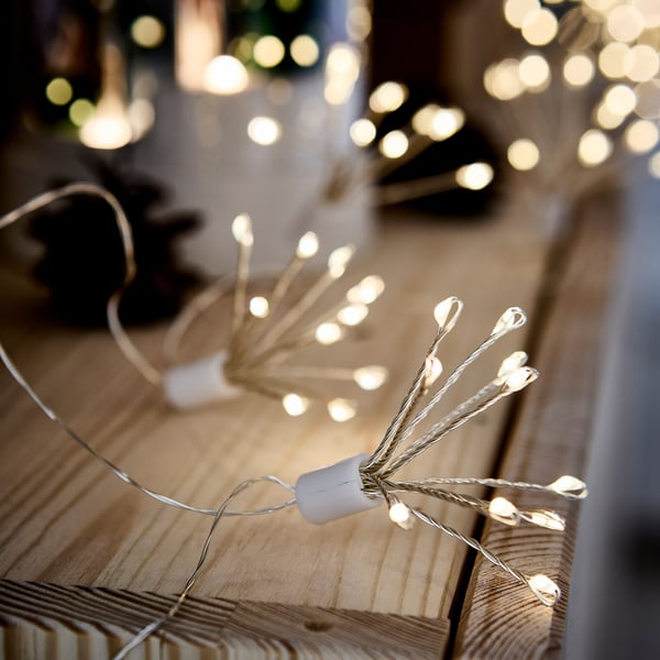 Close-up of a decorative string light with warm, glowing leds on a wooden surface.